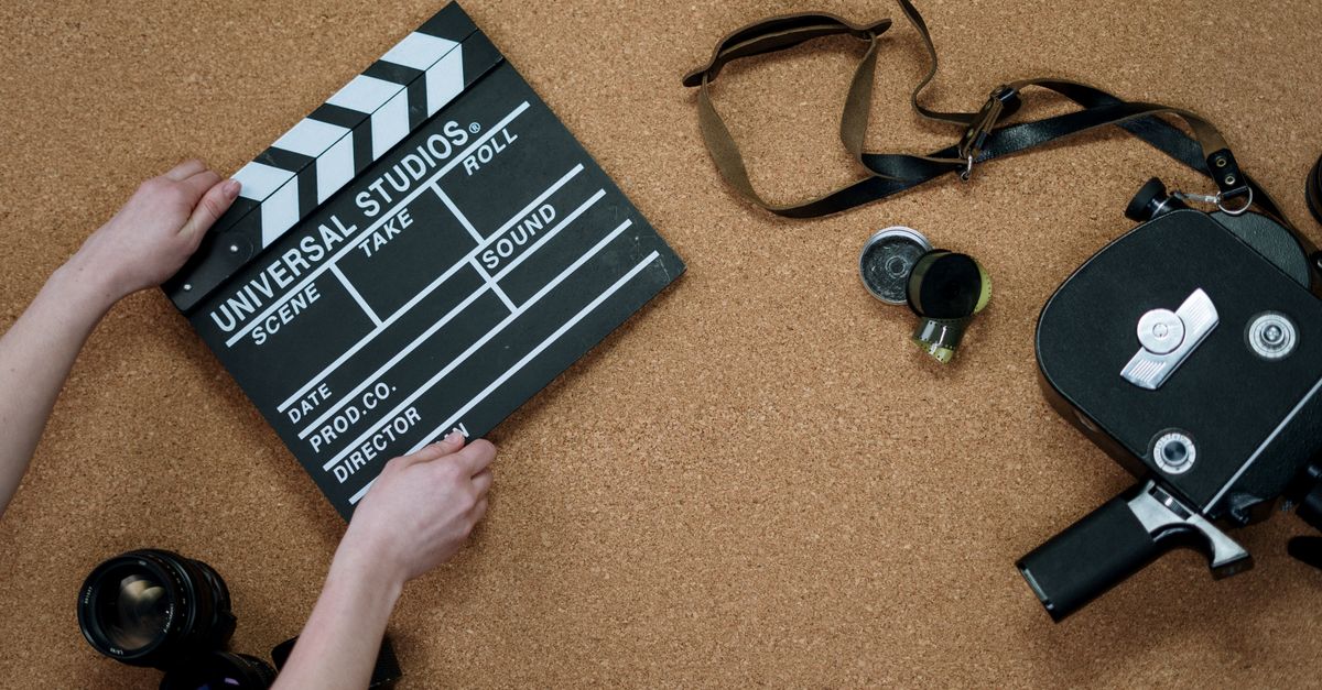 Top view of classic filmmaking tools including a slate and vintage camera on a cork surface.